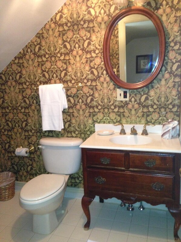 A bathroom with a toilet, sink, and mirror.