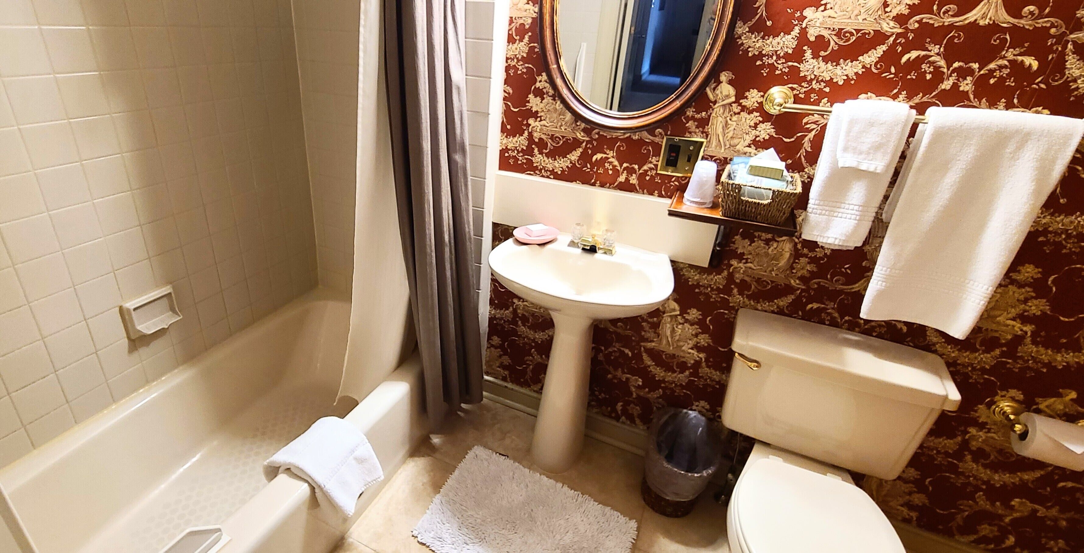 A bathroom with a bathtub, sink, toilet, and a mirror.