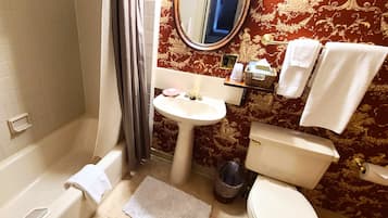 A bathroom with a bathtub, sink, toilet, and a mirror.