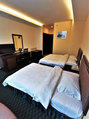 A hotel room with two beds, a desk, a television, and a mirror.
