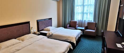 Habitación de hotel con dos camas, un escritorio, una silla y un televisor.