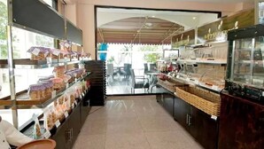 A bakery with shelves of bread and pastries, a counter with baked goods, and a seating area visible through a glass door. - Traders Inn (Bandar Seri Begawan)