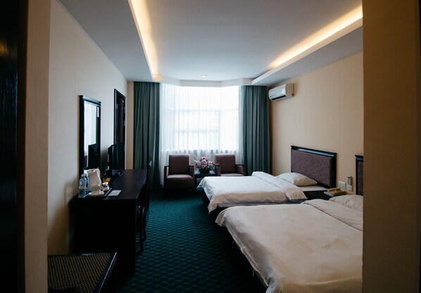 A hotel room with two beds, a desk, a chair, and a large window with curtains.
