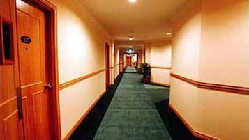 Un pasillo de hotel con piso alfombrado, puertas de madera y pared de color claro.