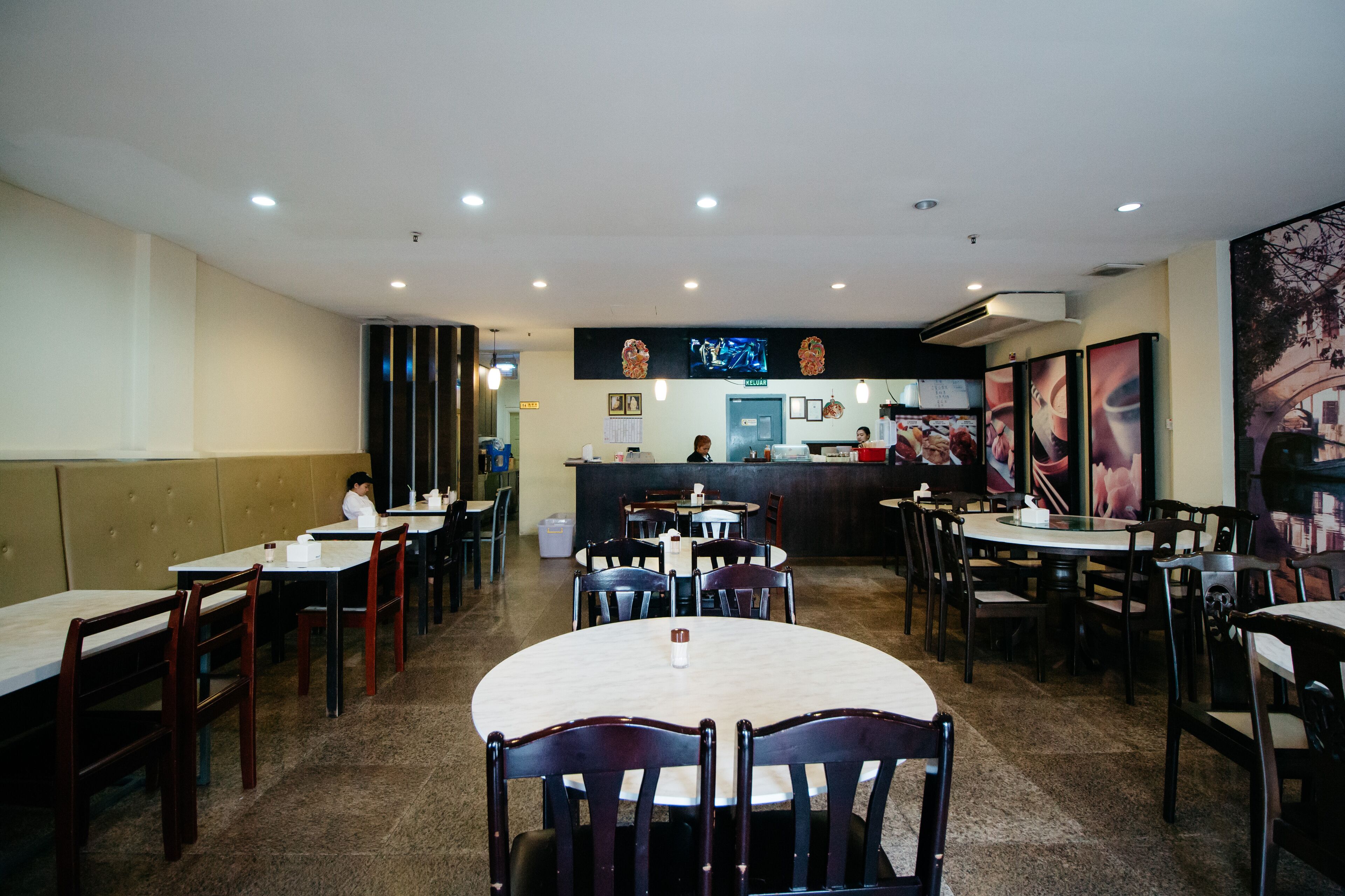 Um restaurante com cabines, mesas, um balcão e um quadro de ementa.