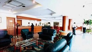 A hotel lobby with a reception desk, seating area with sofas, and a coffee table. - Traders Inn (Bandar Seri Begawan)