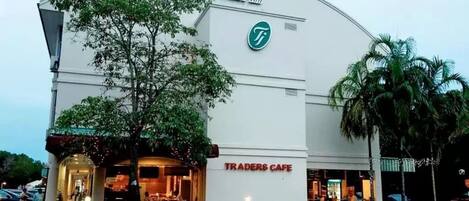 A building with a Traders Cafe sign, a logo with a green circle, and a sign in Arabic.
