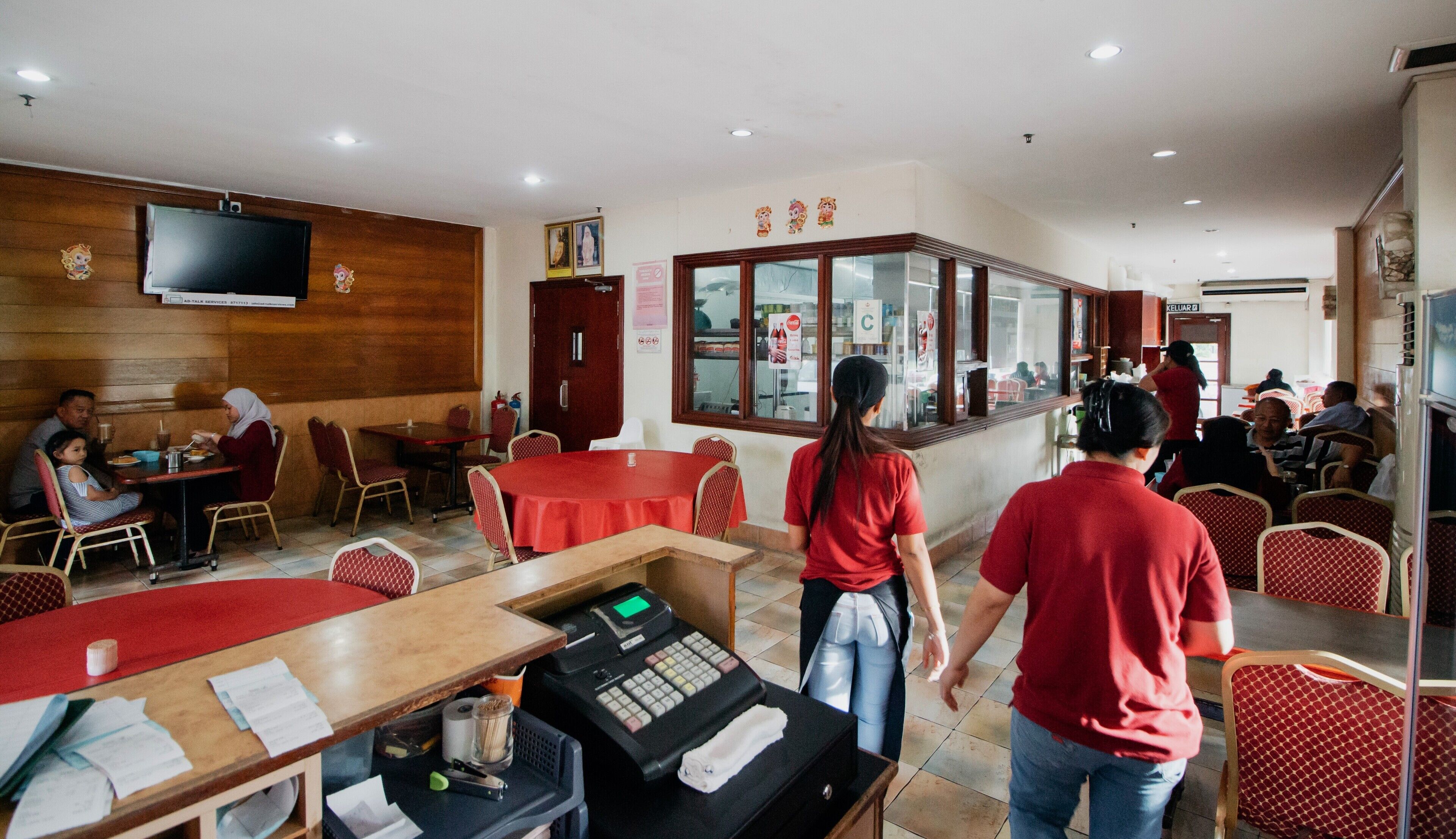 A restaurant with wooden walls, red tables, and a service counter.