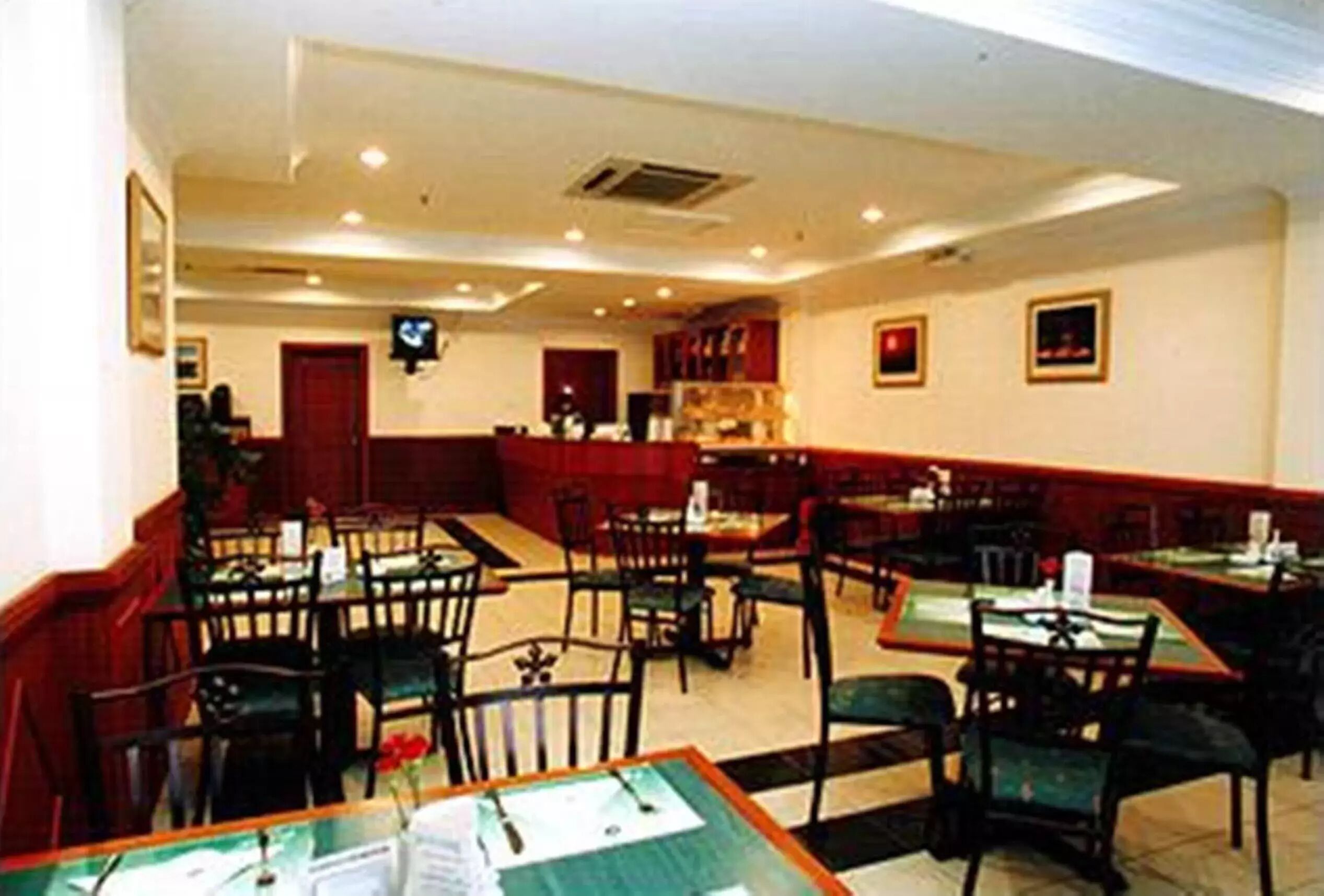 Un restaurante con varias mesas y sillas, una barra y una pared roja decorativa.