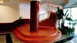 A grand staircase with a red carpet and a central column, leading to an upper floor. - Traders Inn (Bandar Seri Begawan)