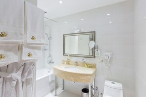 Bathroom features a large curved sink, gold faucet, and a mirror with a gold frame.