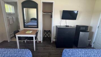 Habitación de hotel con dos camas, un escritorio, una silla, un televisor, un microondas y un refrigerador pequeño.