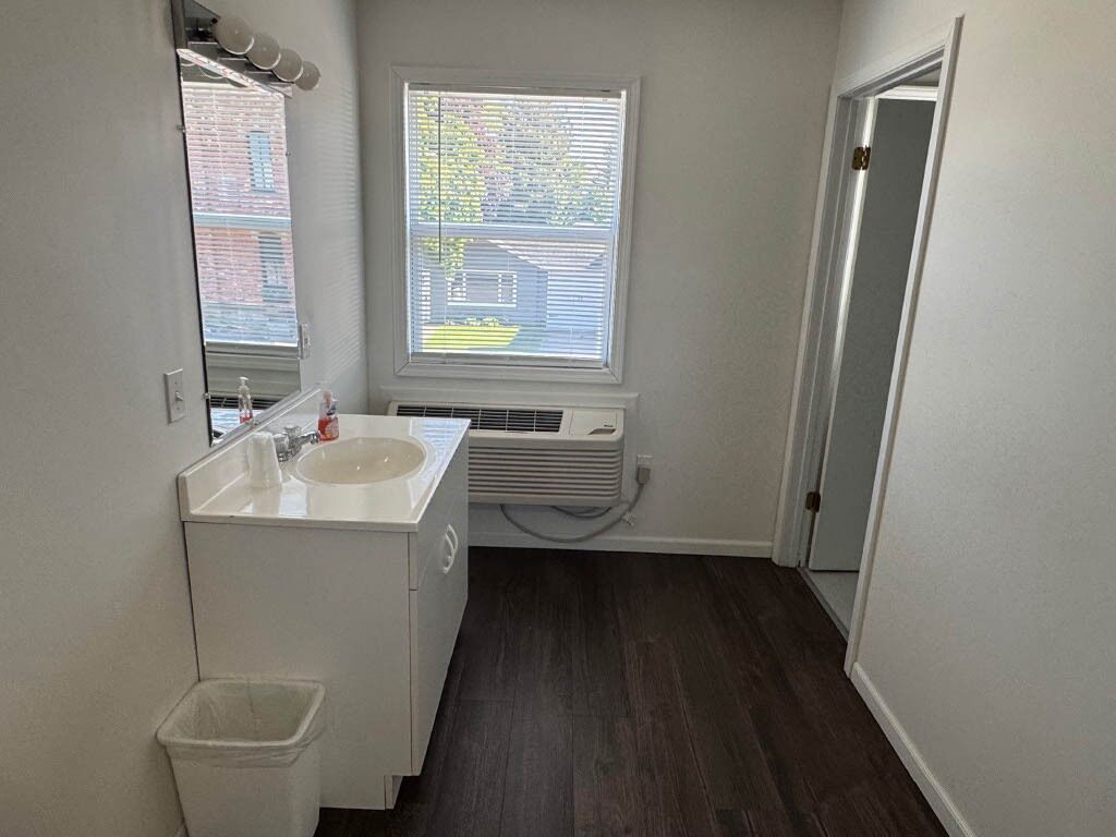 A small bathroom with a white sink, mirror, and window.
