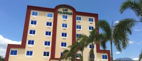 A multi-story hotel with a sign reading "Hotel Las Palmeras."