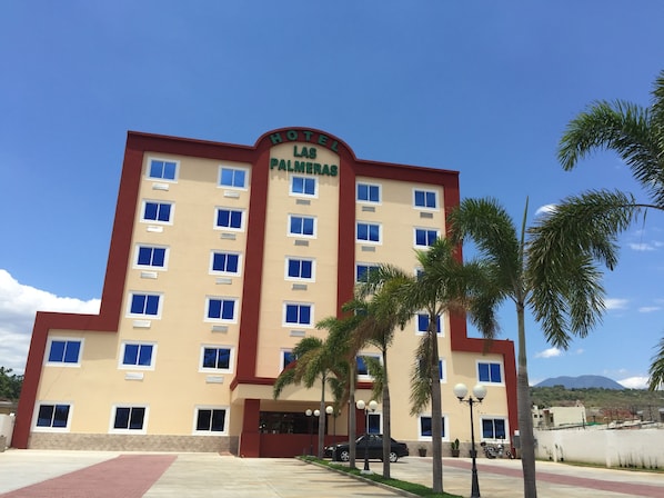 Un hotel de varios pisos con un letrero que dice 'Hotel Las Palmeras'.