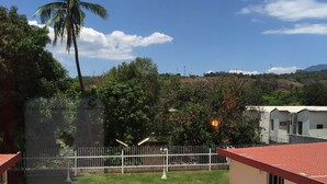 A rectangular swimming pool with a red roof, surrounded by a white fence, and two white lounge chairs. - Hotel Las Palmeras (Sonzacate)