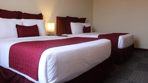 A hotel room with two beds, each with white linens and red bedding. There is a nightstand with a lamp between the beds. - Hotel Las Palmeras (Sonzacate)