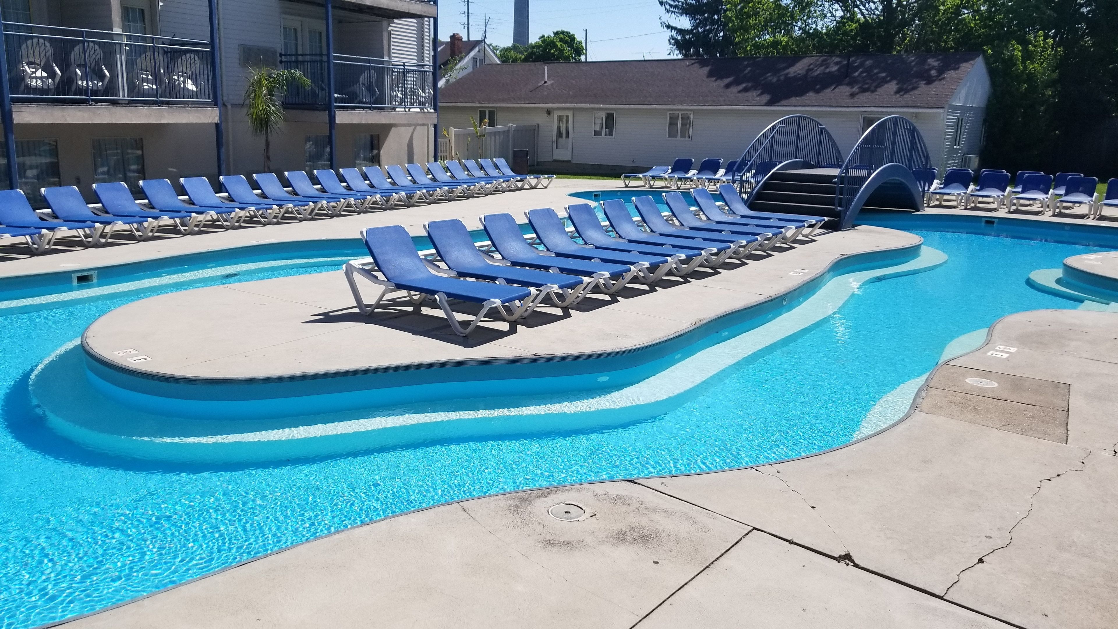 A swimming pool with blue lounge chairs arranged in rows.