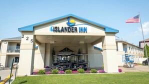 Das Außere des Islander Inn Hotels mit einem freien Eingang, einer Flagge und Golfcarts vor der Fassade.