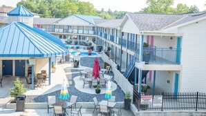 Ein Motel mit mehreren Etagen, Außenbereichen zum Sitzen und einem Pool.