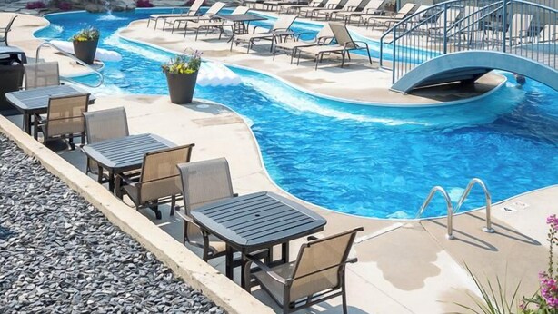 Ein Hotel mit Poolbereich, inklusive Liegestühlen und einer Wasserspielsituation.