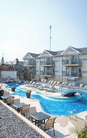 A hotel with a pool area, including lounge chairs and a water feature.