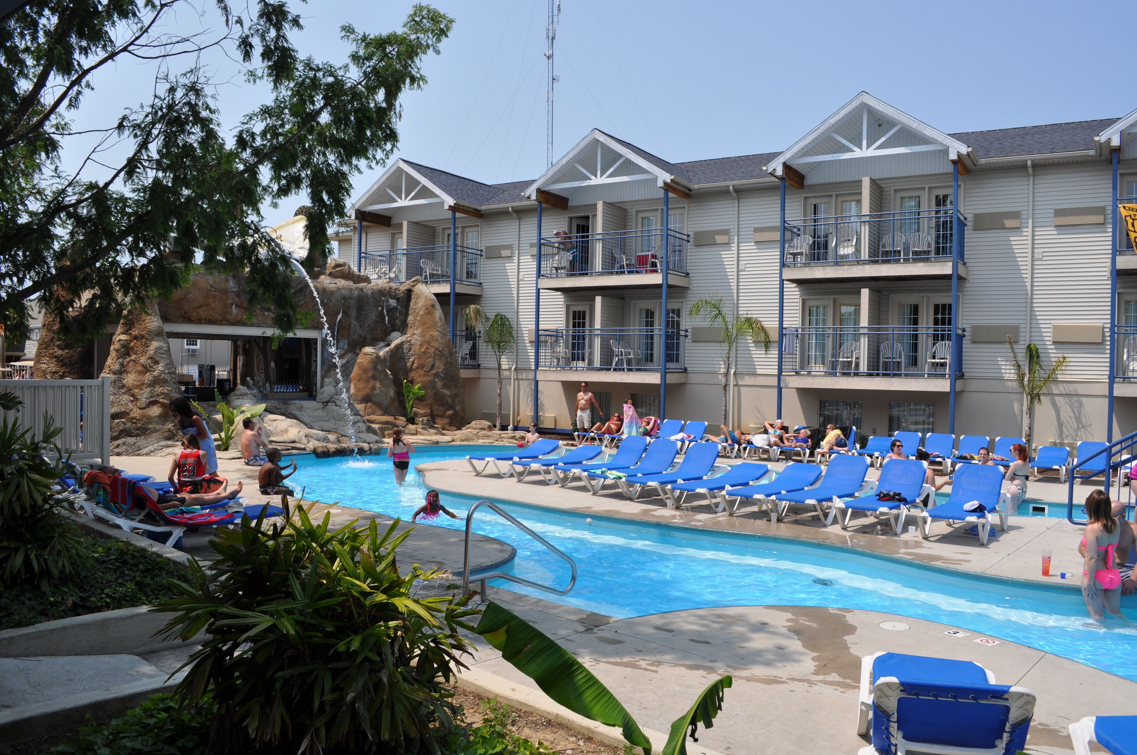 A pool area with blue lounge chairs and a water slide.