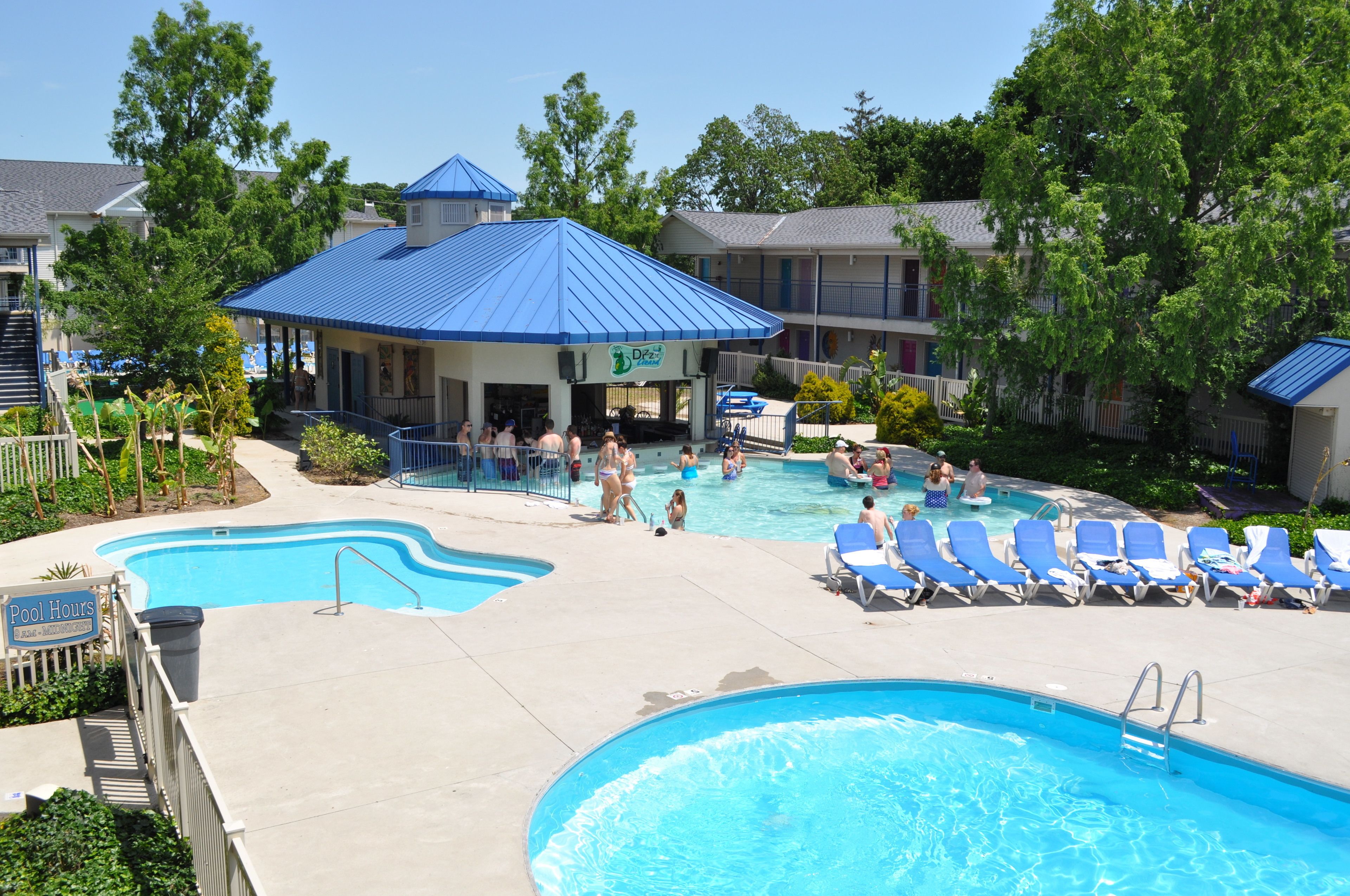 A swimming pool area with lounge chairs and a covered seating area.