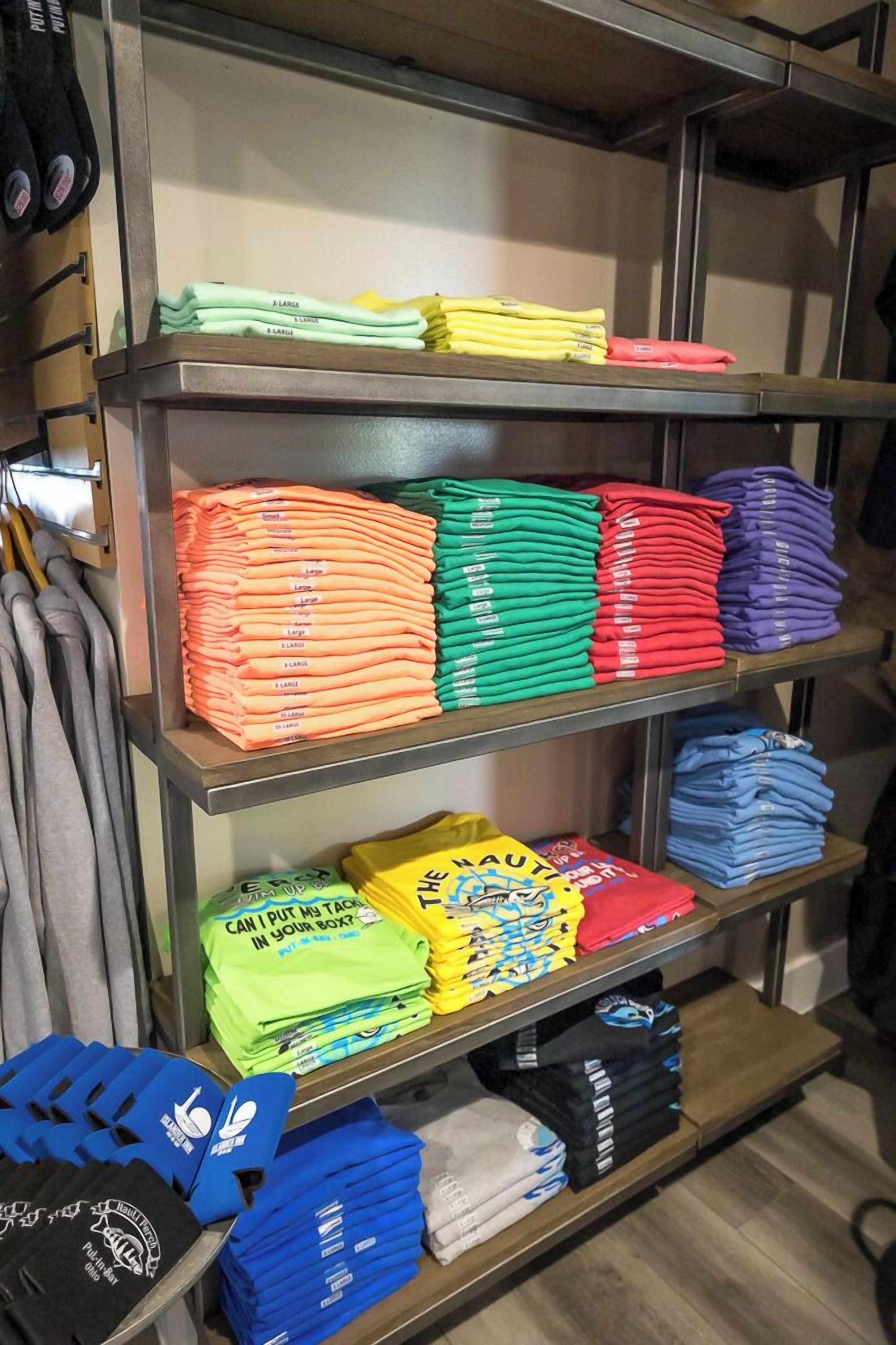 A clothing store with neatly folded shirts in various colors on shelves.