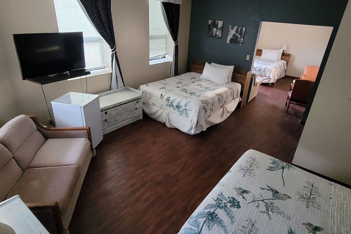 A bedroom with a bed, a TV, a dresser, and a window.