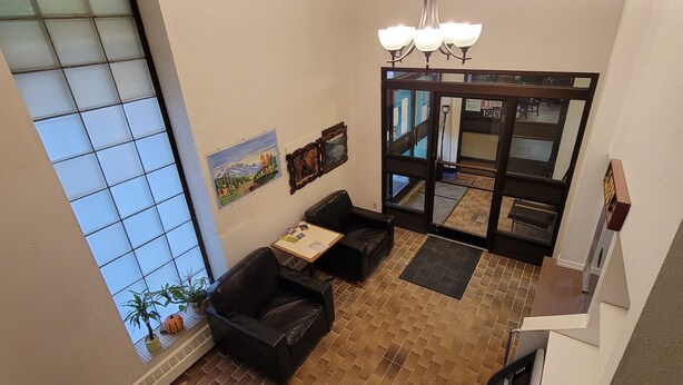 A hotel lobby with a large window, a black leather sofa, a small table, and a door leading to another area. - Cosmopolitan Hotel (Blairmore)