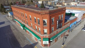 A red brick building with a green awning labeled "Cosmopolitan Hotel" and "The Cos Bar." - Cosmopolitan Hotel (Blairmore)
