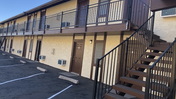 Un edificio a più piani con un balcone, una scala e un parcheggio.