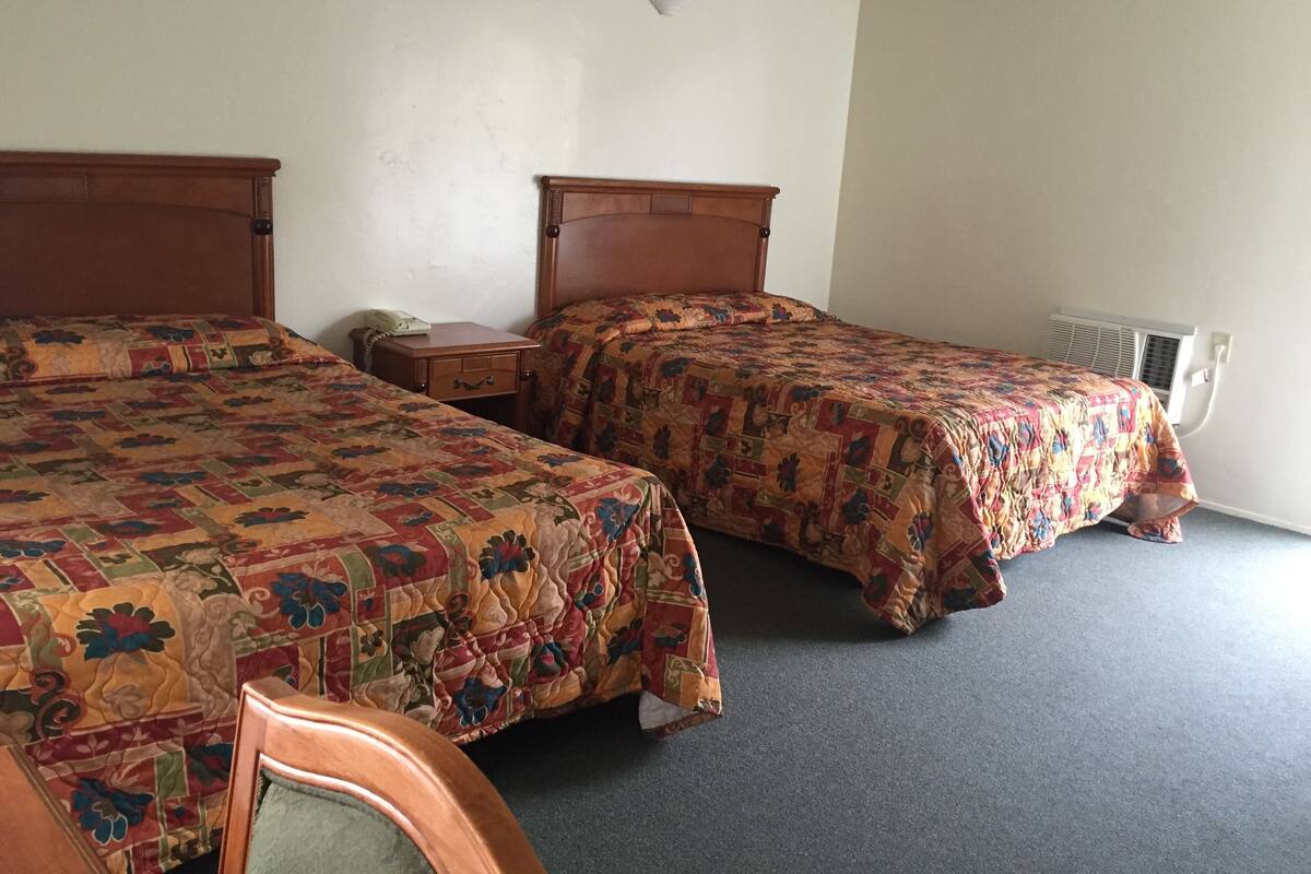 A room with two beds, a bedside table with a lamp, and a radiator.