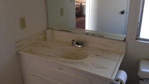 Un bagno con lavandino bianco, uno specchio e un water.