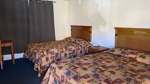 Camera d'albergo con due letti, una testiera in legno, un comodino con il telefono e una sedia.