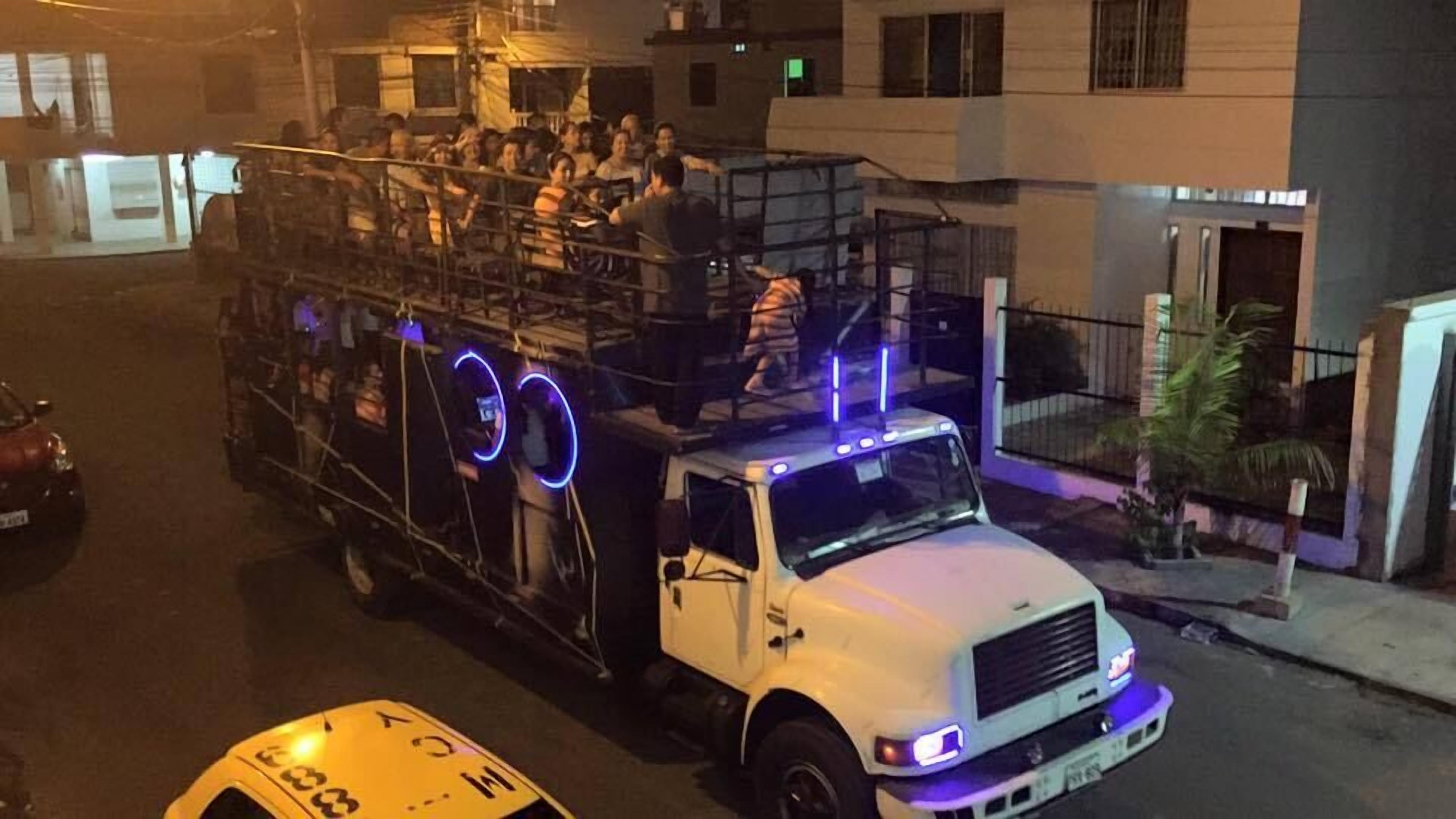 Camión blanco con caja de carga cubierta, estacionado en una calle por la noche.