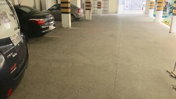 Un parking avec des planchers et des piliers en béton, caractérisé par des piliers rayés et quelques voitures garées.