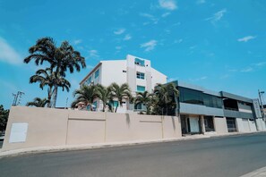 A modern building with a prominent logo on the top, surrounded by palm trees. - Hotel Mar Azul (Manta)