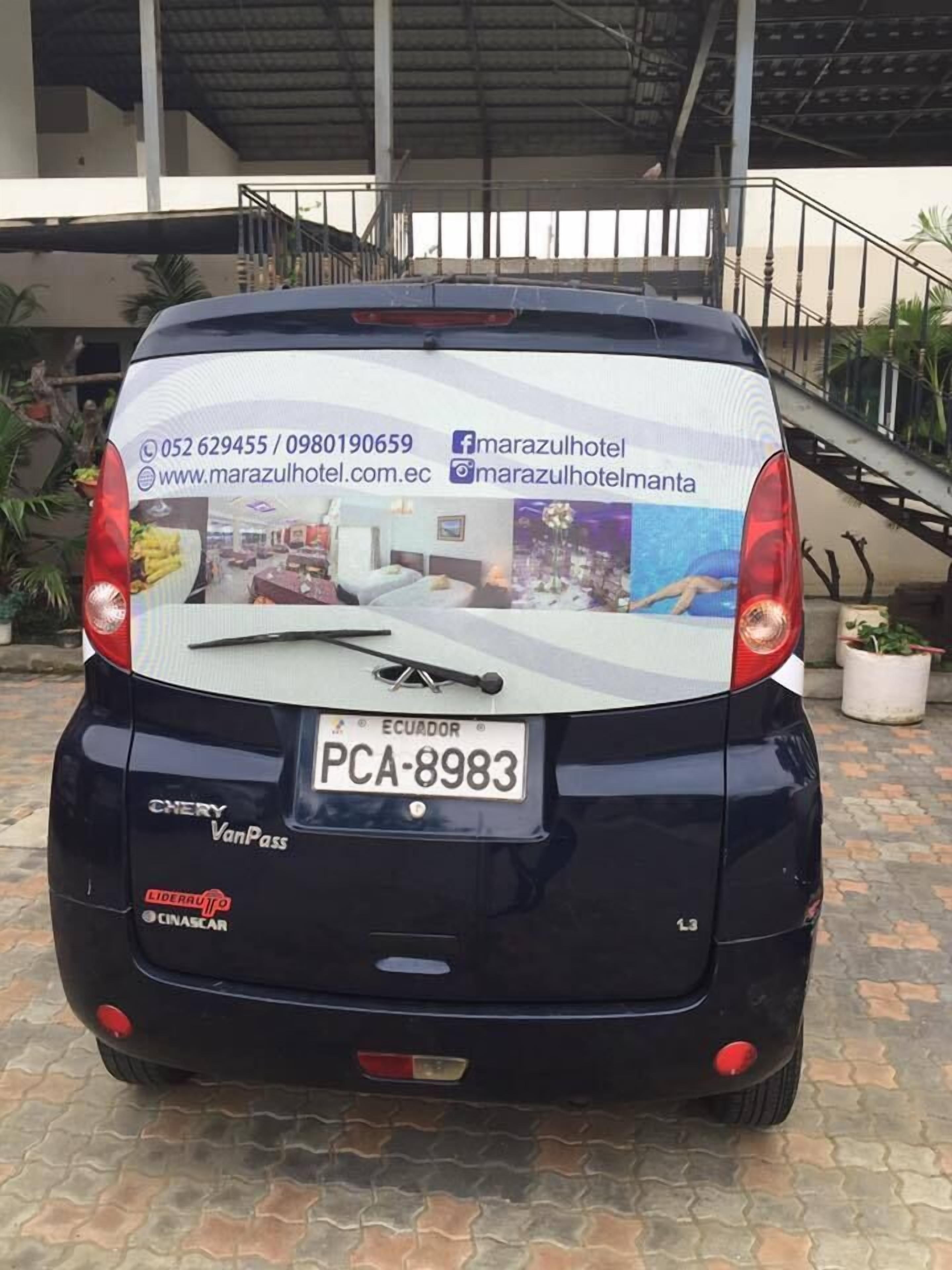 La parte trasera de un vehículo con placa de Ecuador, un adhesivo para camioneta y un espejo retrovisor.
