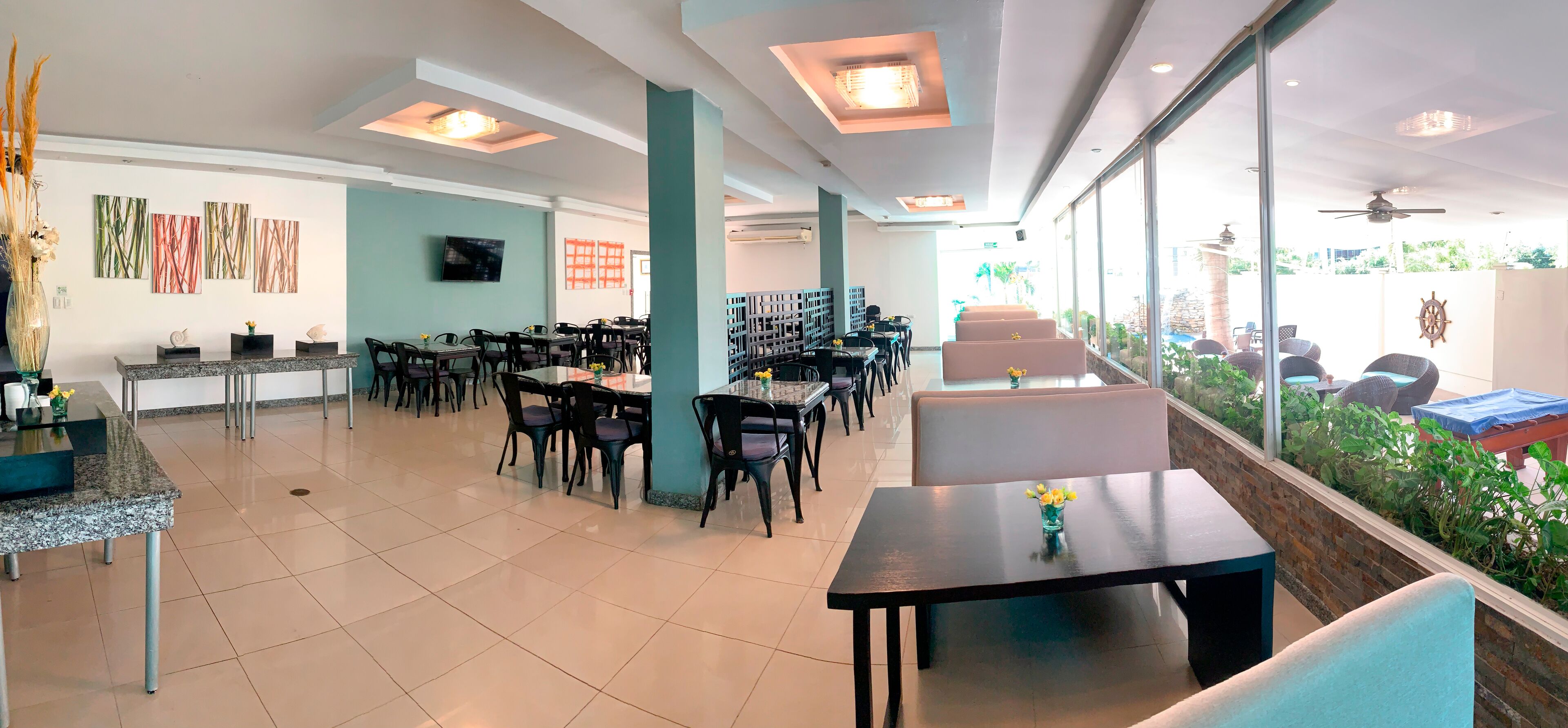 Ein geräumiges Restaurant mit hohen Decken, moderner Einrichtung und großen Fenstern mit Blick auf den Außenbereich.