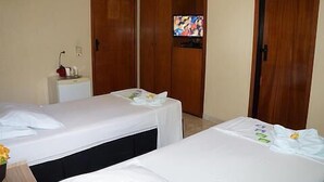 Une chambre d’hôtel avec deux lits, une télévision et une armoire.
