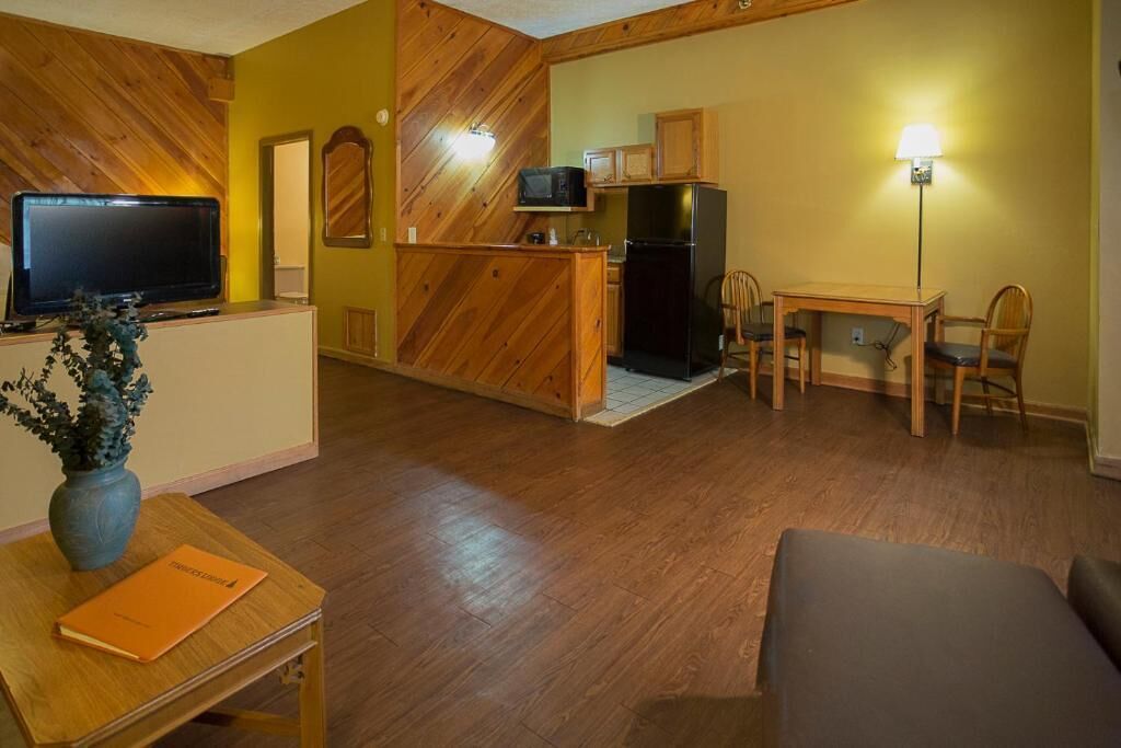 Un espacio habitable compacto con cocina, una mesa de comedor con sillas, un sofá, un televisor y una lámpara.