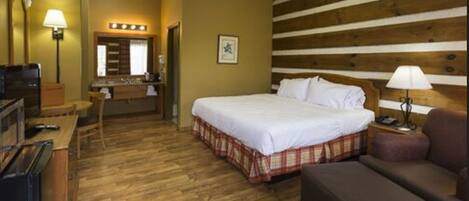 Ein Hotelzimmer mit Bett, Schreibtisch, Stuhl, Sofa und einer Holzwand.