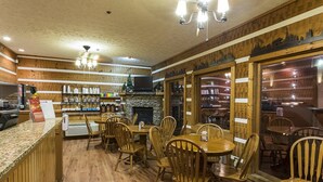 Un restaurante acogedor con paredes de madera, chimenea y diversas opciones de asientos, incluyendo mesas y sillas.