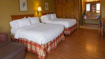 Habitación de hotel con dos camas, un sofá, un escritorio y un baño visible a través de una puerta abierta.