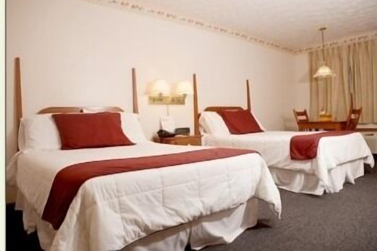 Ein Hotelzimmer mit zwei Einzelbetten, einem kleinen Tisch und einem Stuhl.