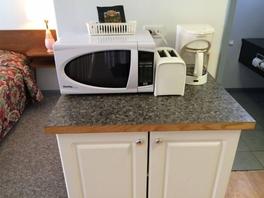 Una kitchenette con microondas, tostadora y cafetera sobre una encimera de granito.