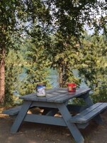 Una mesa de picnic con dos recipientes, rodeada de árboles y un cuerpo de agua.