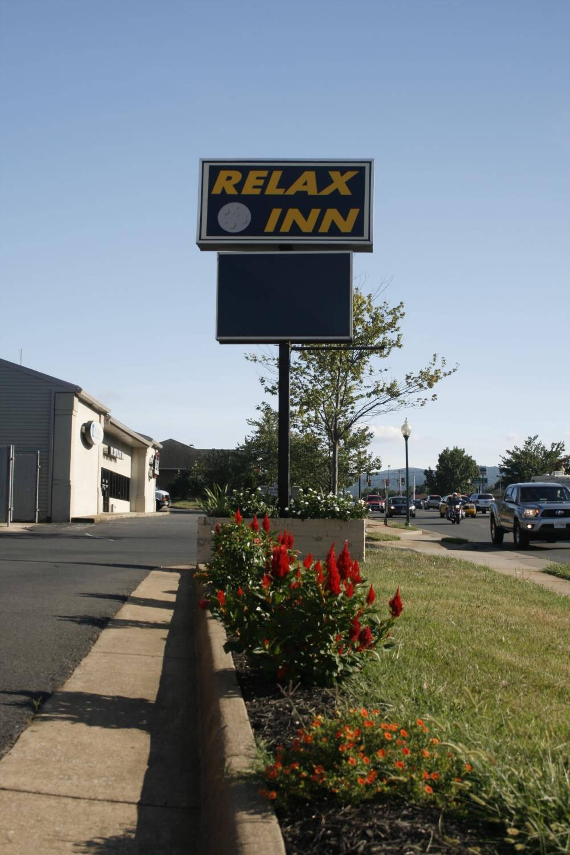 Een bord voor een Relax Inn hotel, met een klok en een groot leeg bord eronder.